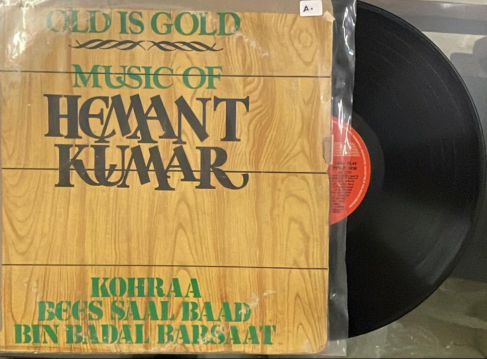 Vinyl record with a wooden cover featuring text, on a white surface.