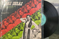 Vinyl record with a colorful cover featuring images of people on a table.