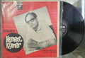Vinyl record with a red cover featuring text and a black and white photo of a person.