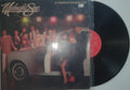 Vinyl record with its cover featuring a band on stage.