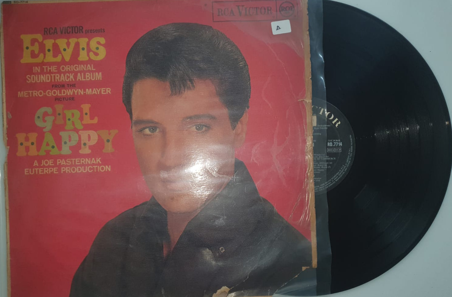 Vinyl record with a red cover featuring a person's face and text.