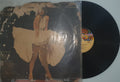 Vinyl record with a cover featuring an artistic depiction of a person in a flowing garment on a light gray background.